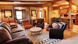 Una sala de estar acogedora con chimenea, sofás de cuero y un comedor con armarios de madera.
