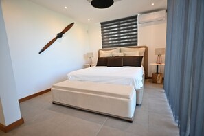 A modern bedroom with a large bed, bedside lamps, a hanging decor piece, and a window with blinds. - Luxury Escape – 5-Star Villa Just 200m from Trou aux Biches Beach (Trou aux biches)