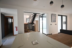 A modern interior with a large marble dining table, a staircase with a unique design, and a fire extinguisher mounted on the wall. - Luxury Escape – 5-Star Villa Just 200m from Trou aux Biches Beach (Trou aux biches)