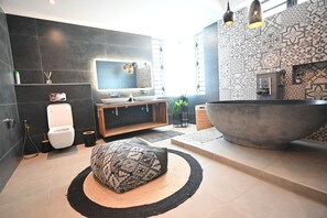 A modern bathroom with a large bathtub, a toilet, a vanity with a mirror, and a television. - Luxury Escape – 5-Star Villa Just 200m from Trou aux Biches Beach (Trou aux biches)