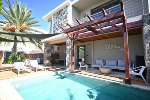 A pool area with lounge chairs, a pergola, and a stone wall. - Luxury Escape – 5-Star Villa Just 200m from Trou aux Biches Beach (Trou aux biches)