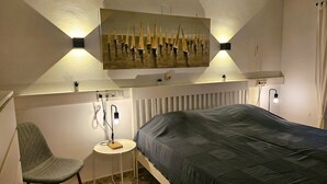 Ein Schlafzimmer mit einem Bett, einem Sessel, einem Heizkörper und einem Bild an der Wand.
