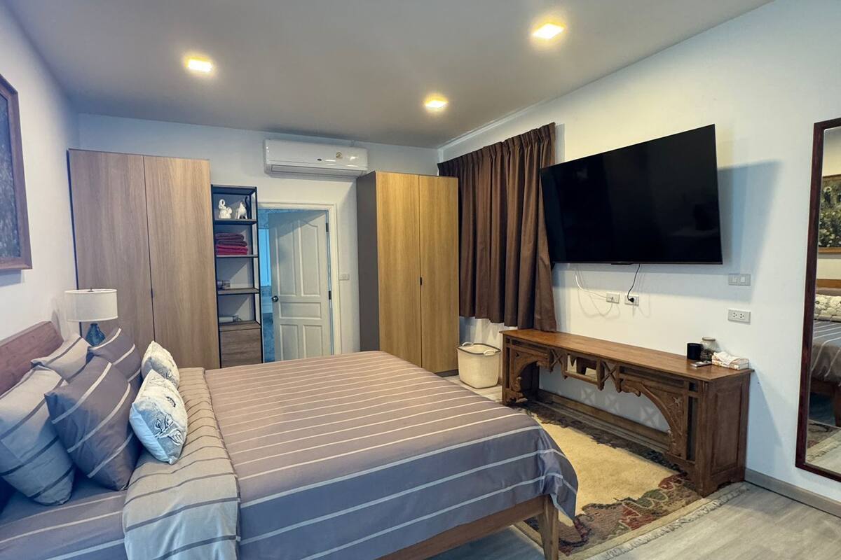 A modern bedroom with a bed, a TV, a wardrobe, and a console table.