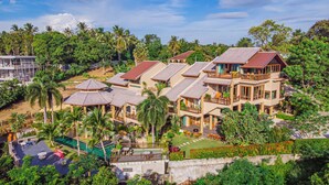 A resort with multiple bungalow-style buildings, each with a sloped roof and a balcony. The resort is surrounded by lush greenery and palm trees. - Bell Seaside Luxury Villa (Rawai)