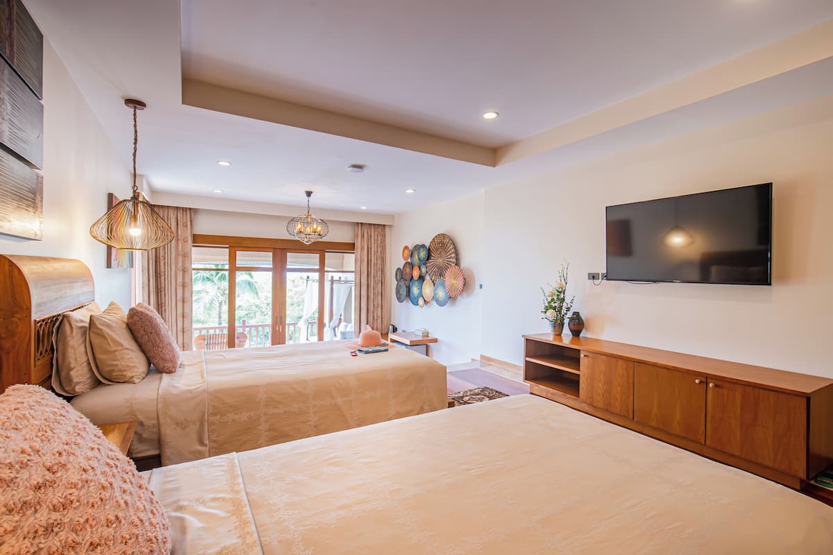 A bedroom with two beds, a TV, and a large window with curtains.