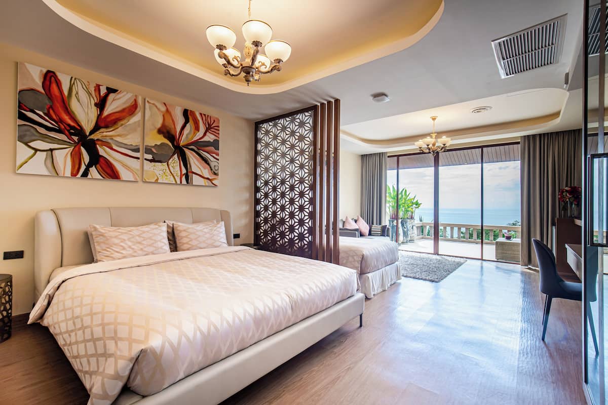 A modern hotel room with a large bed, a balcony with a view, and a decorative wall panel.