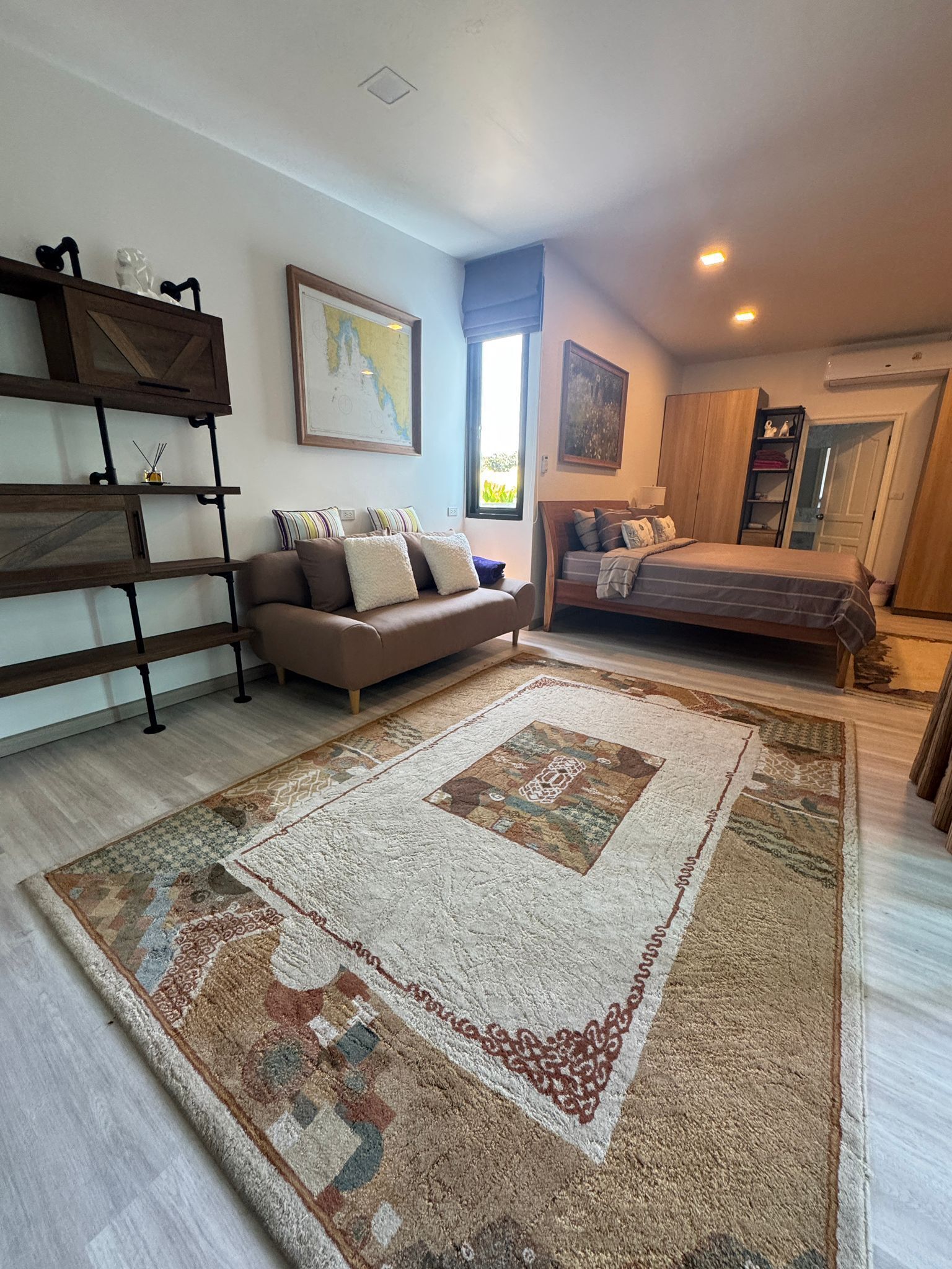 Un dormitorio amplio con una cama grande, un sofá y un armario de madera.