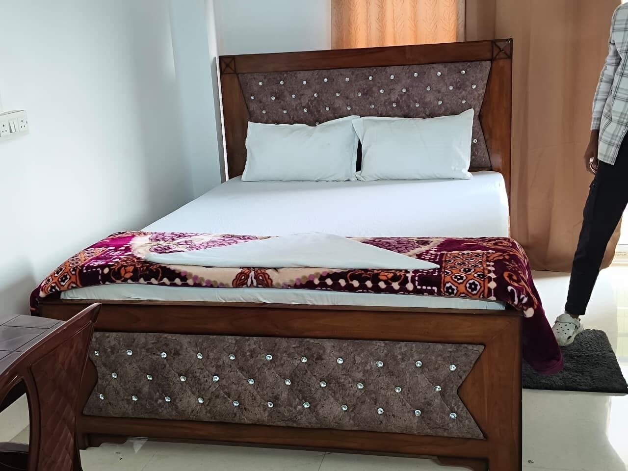 Una cama con estructura de madera y una colcha estampada.