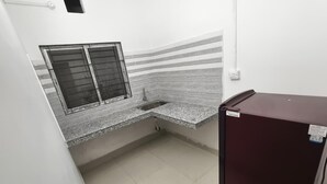 A small kitchen with a window, a sink, and a refrigerator. - Jironi Residency In (Guwahati)