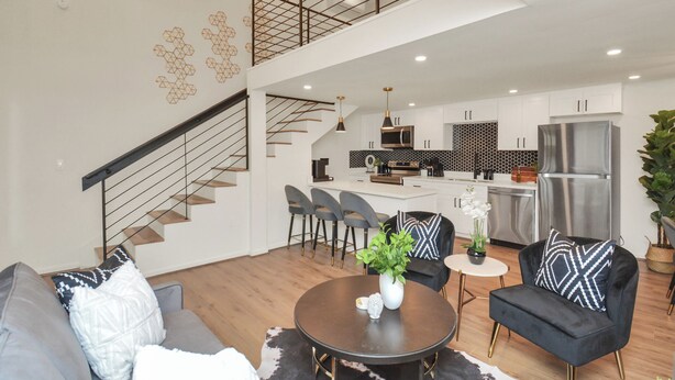 Ein modernes Wohnzimmer mit Treppe, Essbereich und Küche.