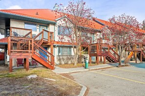Un bâtiment doté de plusieurs escaliers en bois menant à une terrasse, entouré d’arbres aux feuilles rouges.