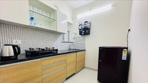 Una cocina compacta con armarios de madera, encimera negra, cafetera y refrigerador.