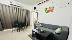 Una sala de estar con sofá, una mesa de centro, una mesa de comedor con sillas y un equipo de aire acondicionado.