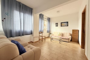 Ein Wohnzimmer mit einer Couch, einem Couchtisch, einem Sessel, einem kleinen Tisch und einem Schrank.