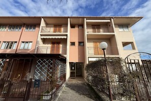 Un immeuble résidentiel à plusieurs étages, doté de balcons, d’une entrée sécurisée et surplombant un ciel dégagé.