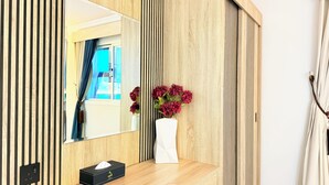 A modern bathroom with a wooden panel wall, a mirror, a vase with flowers, and a tissue box on a wooden counter.