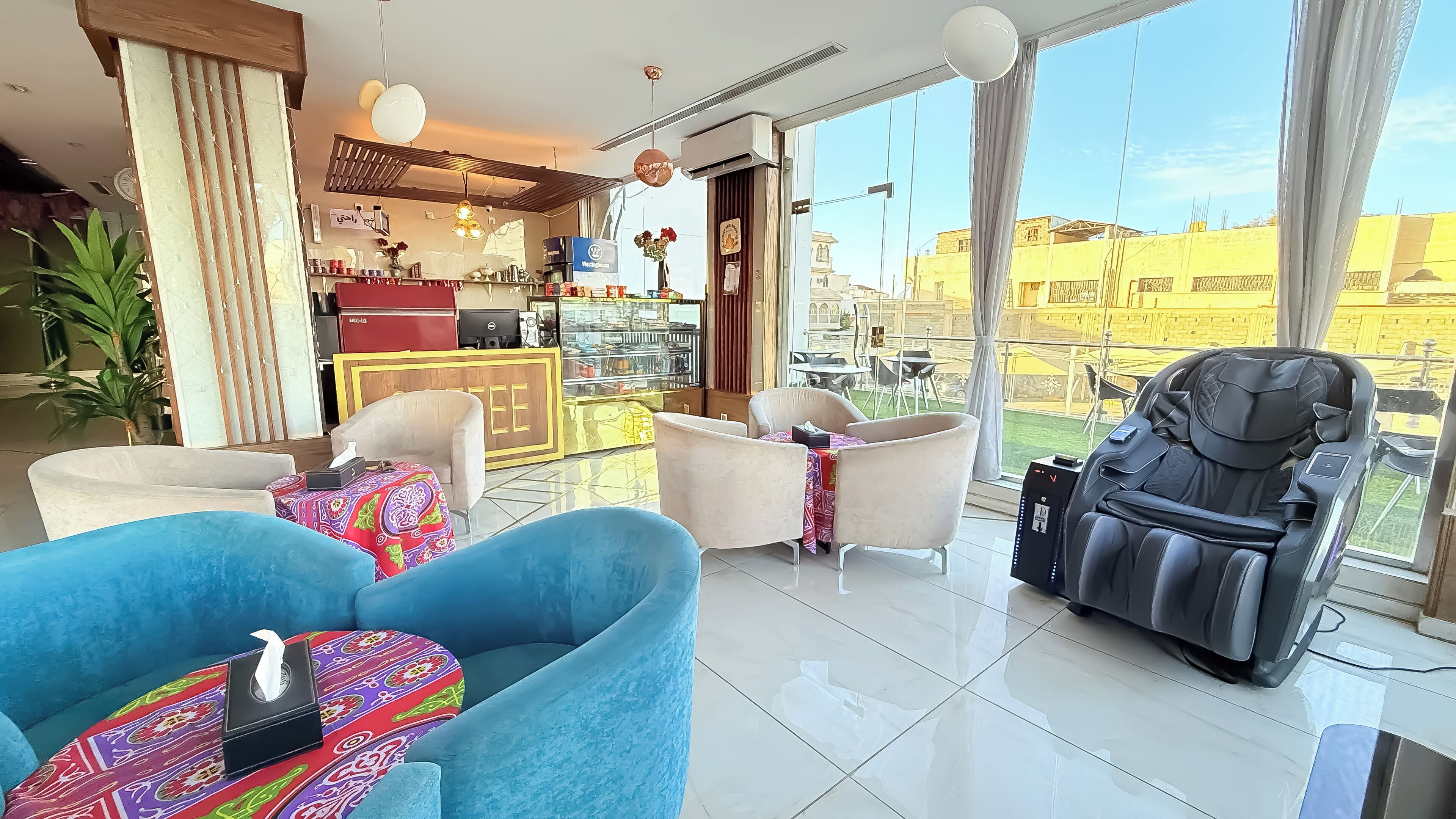 A modern hotel room with a balcony, a massage chair, and a dining area with a view.