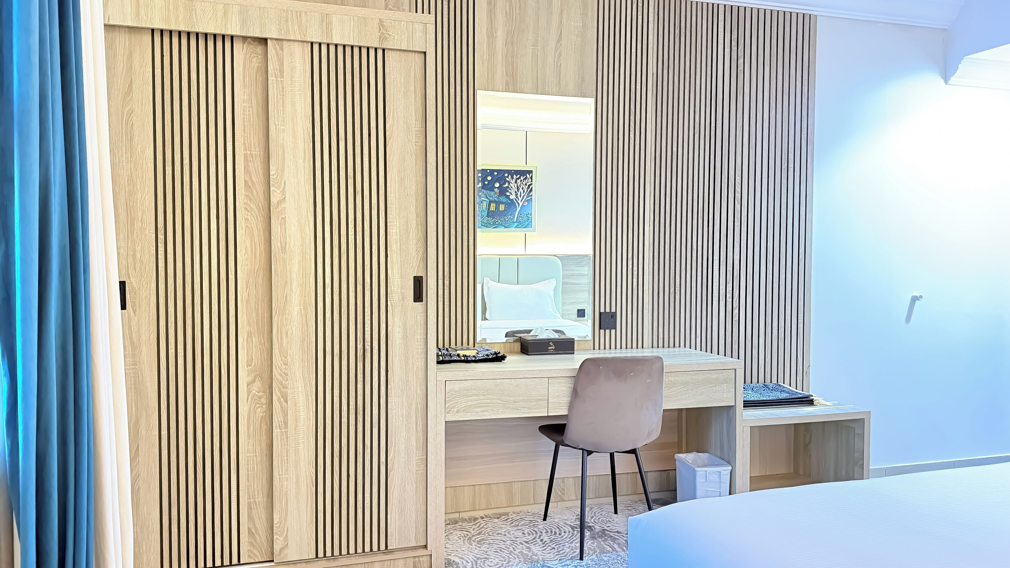 Een moderne slaapkamer met een houten garderobe, bureau en bed.