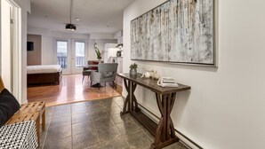 Een moderne woonkamer met een houten bank, een grijze fauteuil en een eettafel met decoratieve objecten.