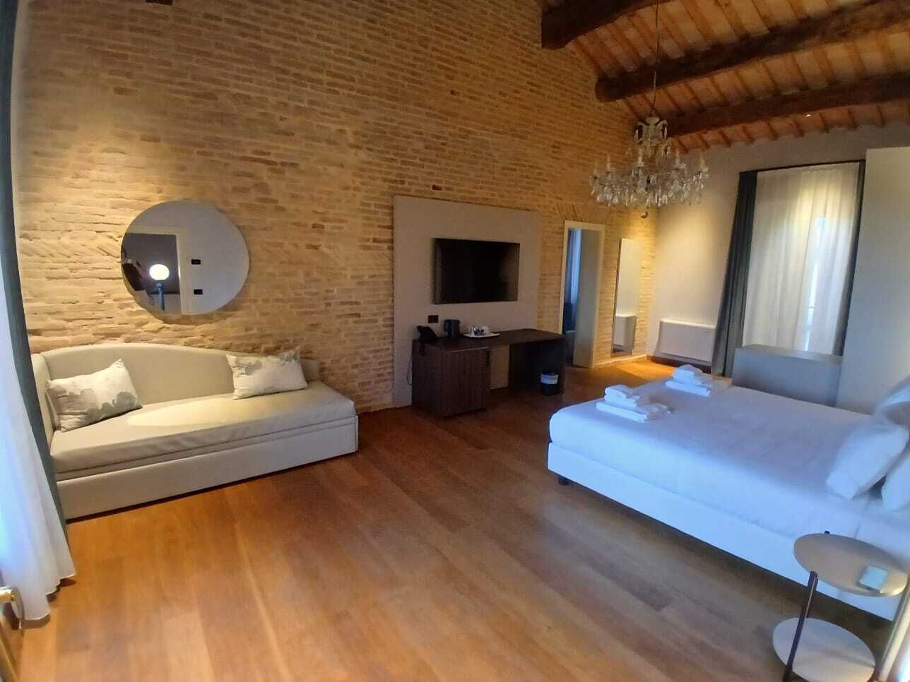 Quarto com parede de tijolos, televisão de tela plana, sofá, cama e lustre.