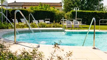 Una piscina con ringhiere in metallo, lettini e solarium piastrellato.