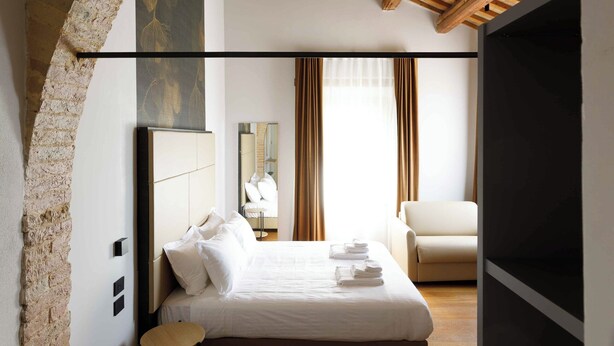 Una camera da letto con un letto grande, un soffitto in legno e un arco in mattoni.