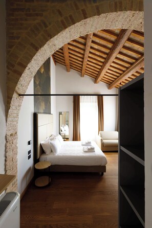 A bedroom with a large bed, a wooden ceiling, and a brick archway. - Relais Villa Roncuzzi (Russi)