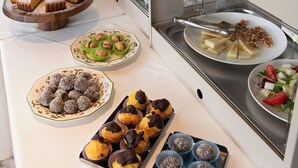 Un buffet con diverse pietanze, tra cui torte, pasticcini e salumi.