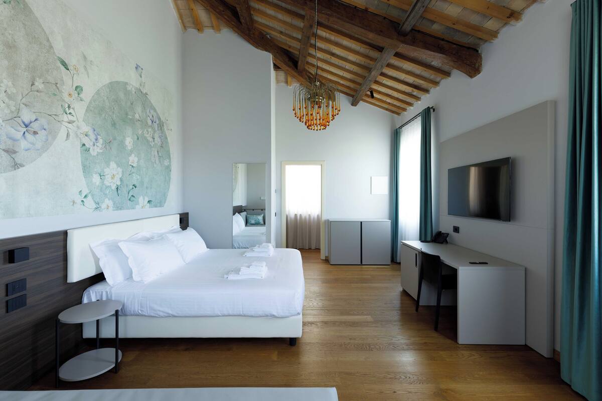 A modern hotel room with a large bed, a desk, and a TV.