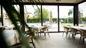 Un espace repas avec des tables et des chaises, une piscine et une vue sur l’extérieur.