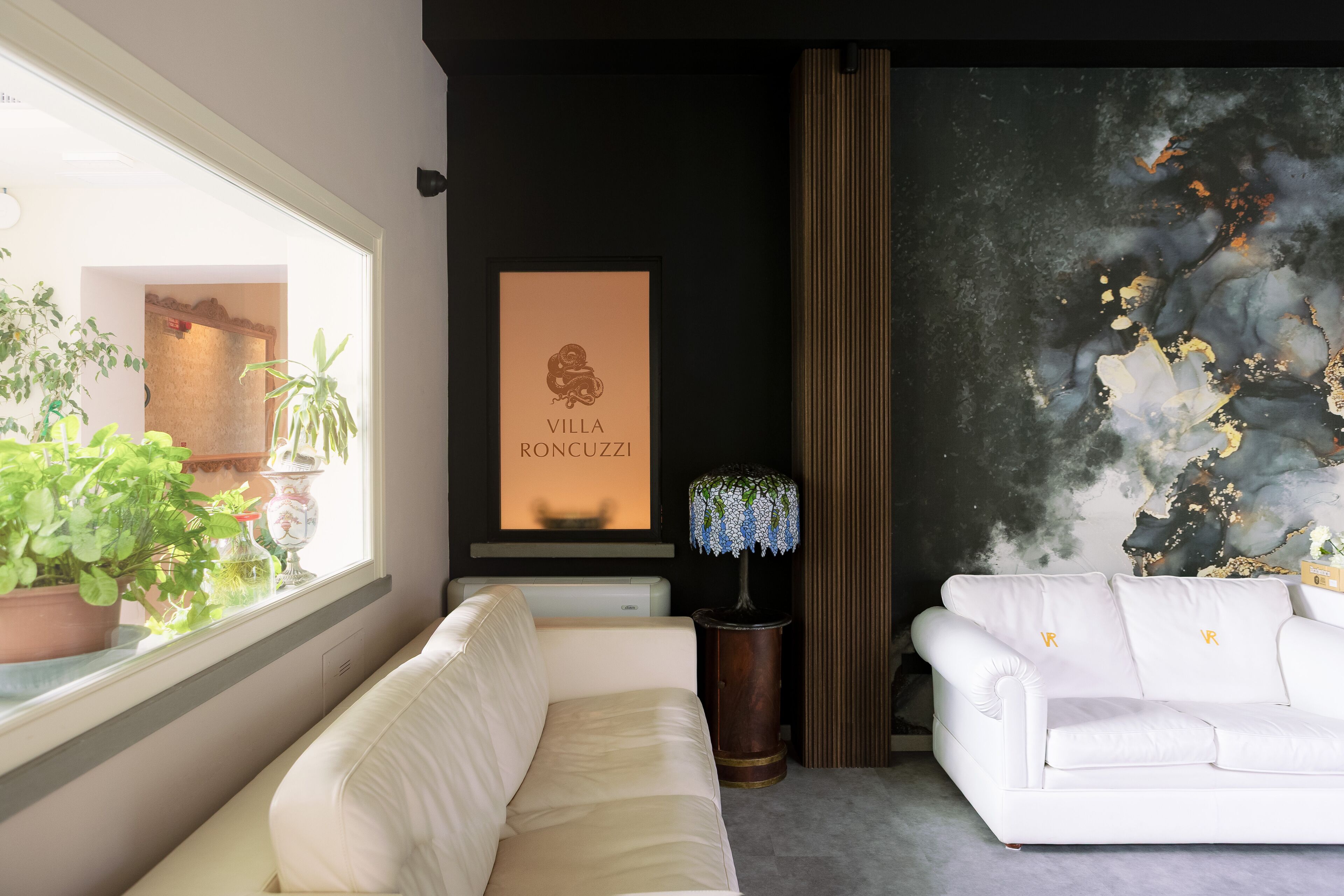Una sala de estar moderna con un sofá blanco, una lámpara decorativa y una obra de arte enmarcada en la pared.