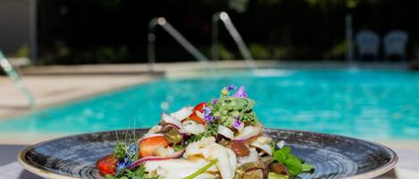 A plate of seafood salad with a pool in the background.