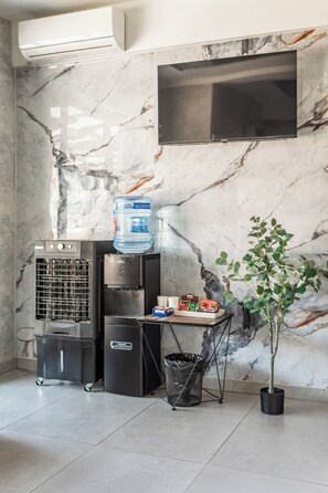 A modern kitchen with a water dispenser, a coffee machine, and a trash bin. - Beshchinor Hotel  (Tashkent)