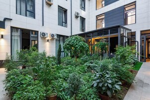 A courtyard with potted plants, a glass door entrance, and a building with multiple windows and air conditioning units.