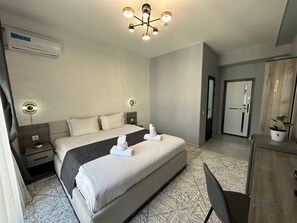 Une chambre d’hôtel moderne, dotée d’un grand lit, de tables de chevet, d’un bureau et d’une armoire.