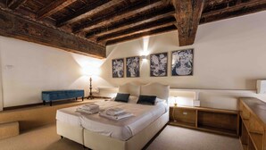 Ein Schlafzimmer mit einem großen Bett, Holzbalken, einer blauen Bank und Bildern an der Wand.