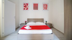 Une chambre à coucher avec un lit, deux tables de chevet et trois tableaux encadrés accrochés au mur.