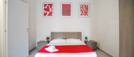 A bedroom with a bed, two bedside tables, and three framed pictures on the wall.