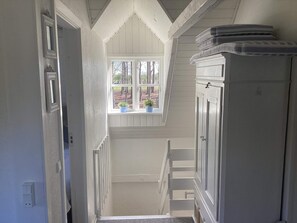 A narrow stairway with a window at the top, leading to a landing with a white cabinet. - 5 Star Holiday Home in Ansager (Ansager)