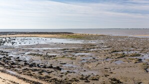 Eine Küstenlandschaft mit Sandstrand, Felsenformationen und einer fernen Küstenlinie.