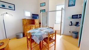 Ein Essbereich mit einem runden Tisch für vier Personen, Holzstühlen, einer Kommode mit Fernseher und einem Fenster mit Blick.