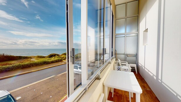 Ein Balkon mit Meerblick, einem weißen Tisch und einem Stuhl.