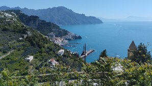 Eine Küstenstadt mit terrassenförmig angeordneten Häusern, einem Jachthafen und weiter Aussicht auf das Meer und ferne Berge.