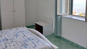 Ein Schlafzimmer mit Bett, einem an der Wand montierten Fernseher, einem Fenster mit Aussicht und einem Kleiderschrank.
