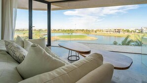 Un soggiorno moderno con una grande finestra che si affaccia su un campo da golf e uno specchio d'acqua.