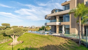 Una casa moderna a più piani con piscina, prato curato e cielo sereno.