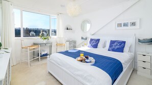 Une chambre d’hôtel avec un grand lit, un bureau, une chaise, une fenêtre donnant sur la ville et un plateau de petit-déjeuner posé sur le lit.