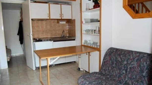 Un ambiente compatto con angolo cottura, divano e tavolo da pranzo.