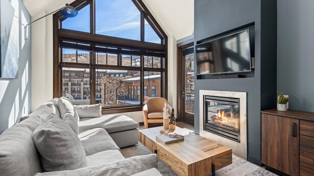 Ein modernes Wohnzimmer mit großem Fenster, Kamin, Sofa und Couchtisch.