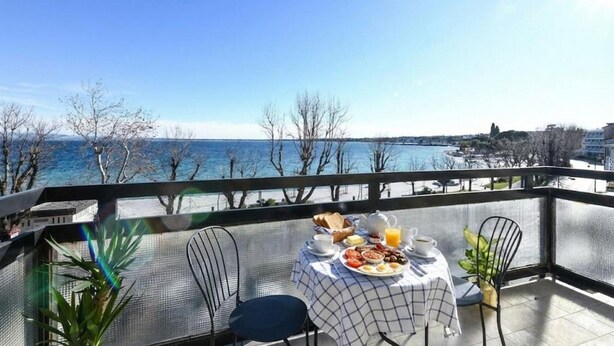 Varanda com mesa posta para o pequeno-almoço e vista para a costa.